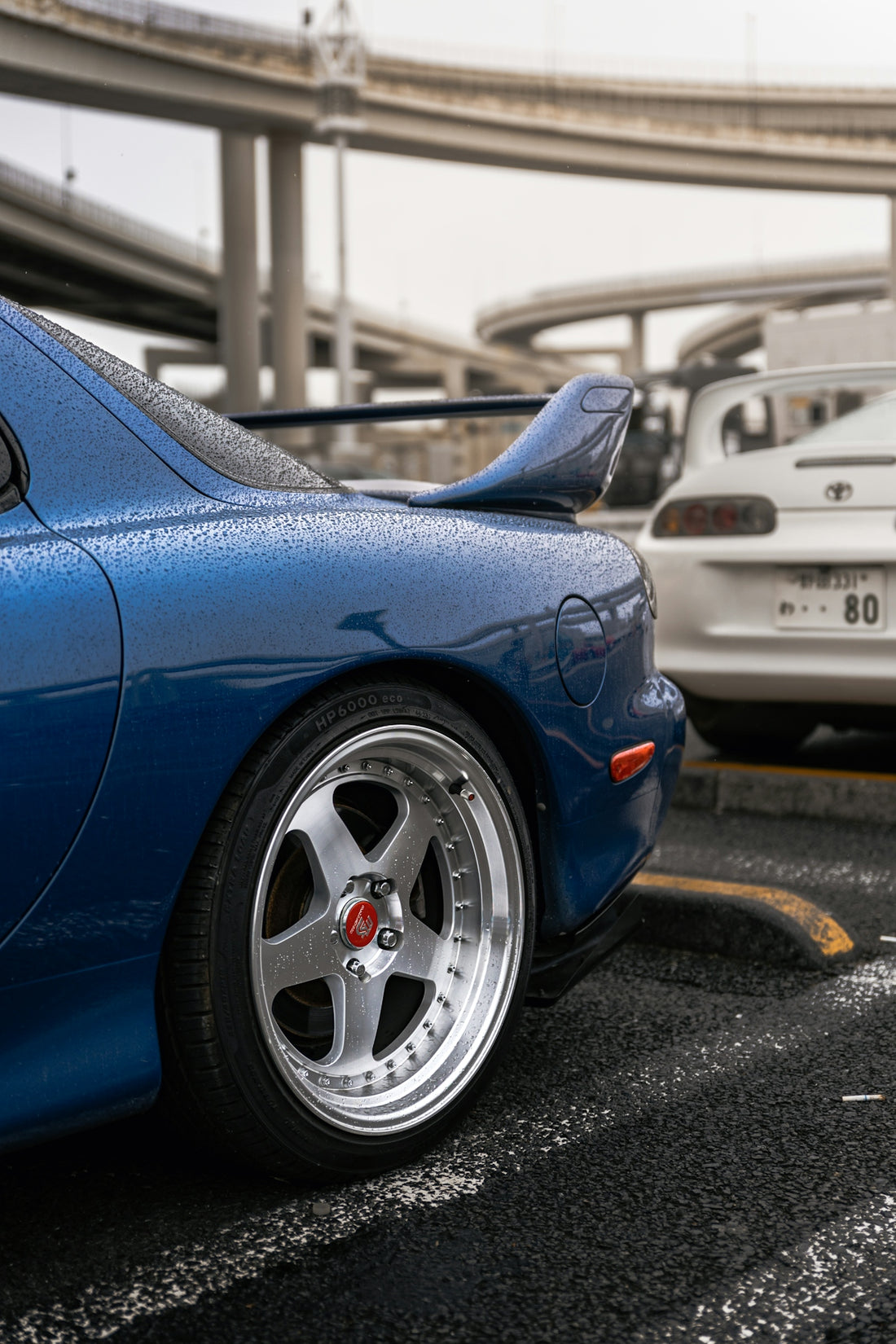 Blue sports car with chrome wheels in rain.